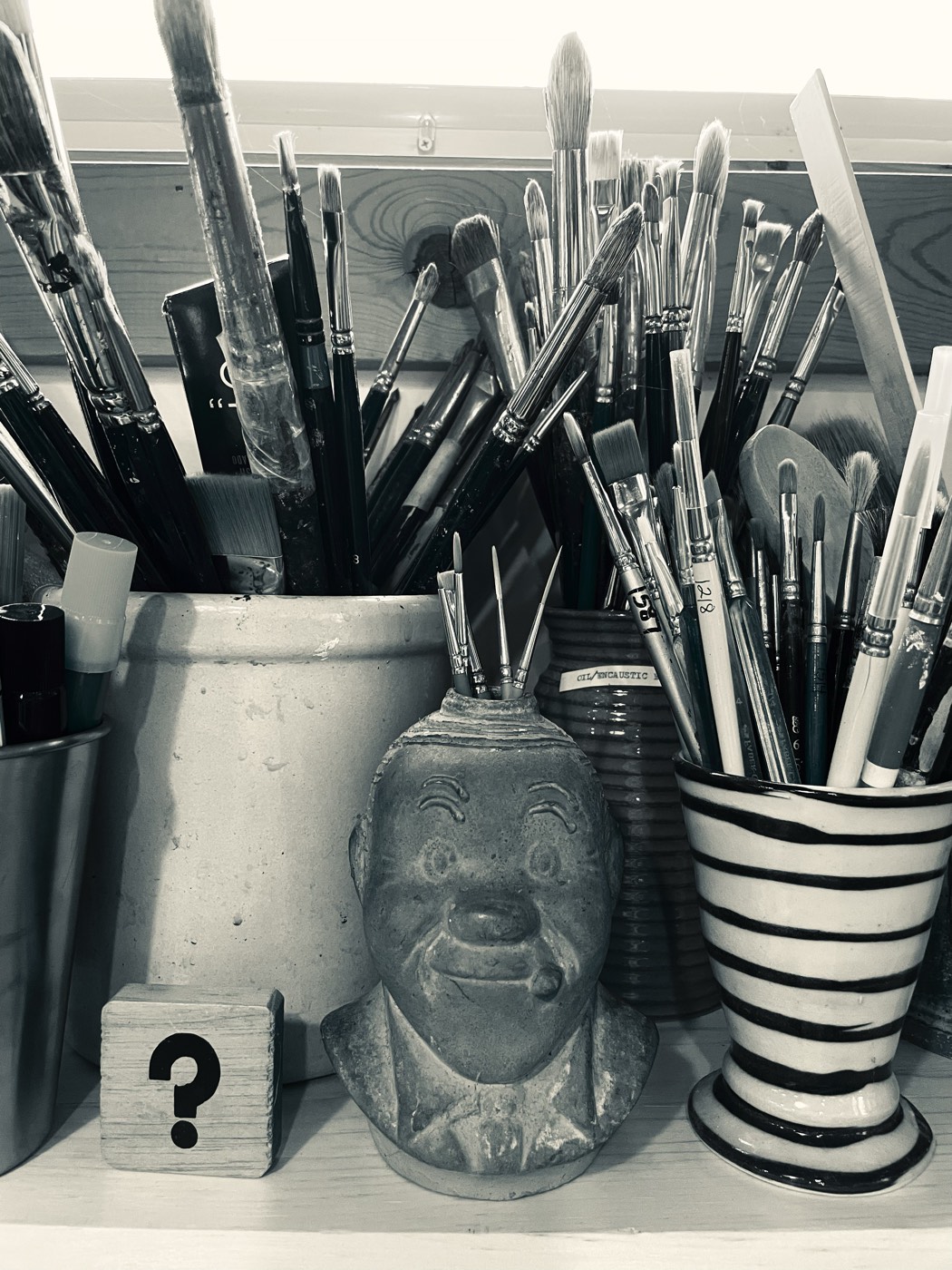Cups of paintbrushes on the studio desk, in black and white